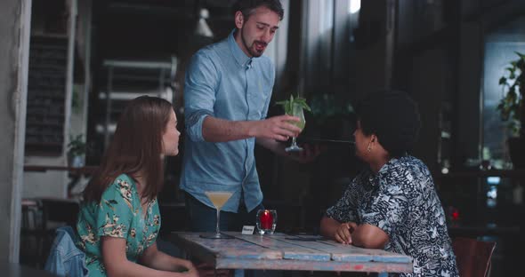 Waiter delivering coctails to the young couple on dinner date