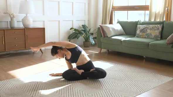 Sporty Indian Woman Doing Stretching Exercise without Yoga mat at home. Black Sportswear 