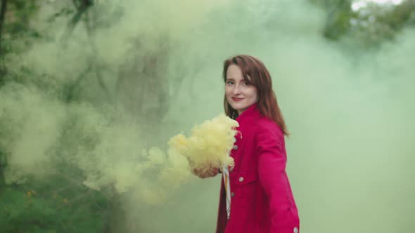 Woman with Color Smoke Bomb Walking Through Forest