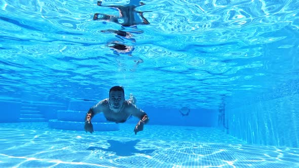 Vacation concept. Happy young man swimming inside the swimming pool. 