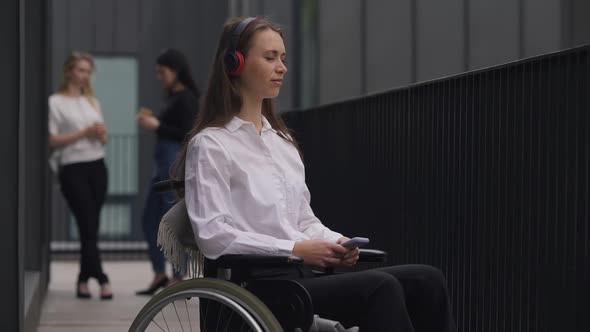 Slim Beautiful Young Disabled Woman Enjoying Music in Headphones on Break Outdoors