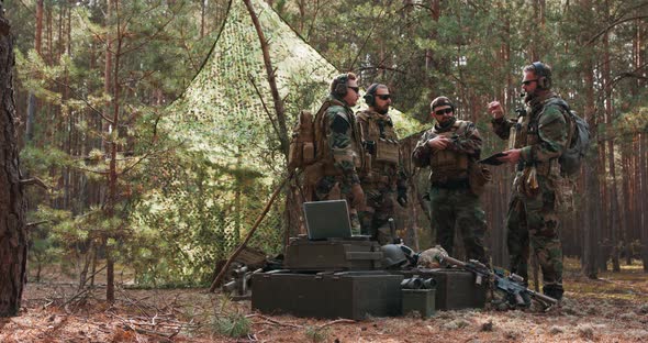 A Group of Middleaged Bearded Soldiers in Uniforms and Tactical Vests Discusses the Action Plan and