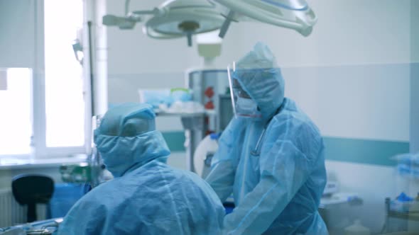 Medical workers in protective suits in operating room