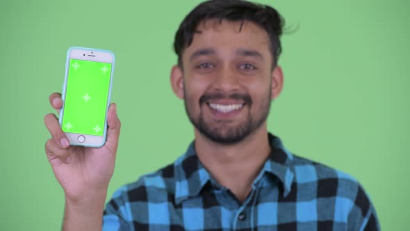 Face of Happy Young Bearded Persian Hipster Man Showing Phone