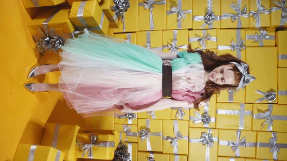 A Happy Woman with Natural Red Hair Dressed in a Cute Dress Poses Against the Background of Many