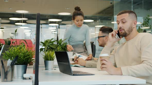 Slow Motion of Men and Women Working in Shared Office Talking Using Laptops Calling