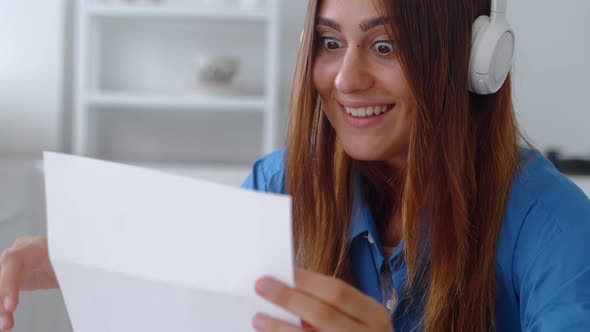 Attractive Woman in Blue Shirt Sit on Kitchen Hold in Hands Sheets Read Great News in Letter Feels