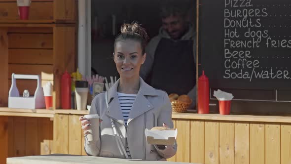 Happy woman buying coffee in food booth