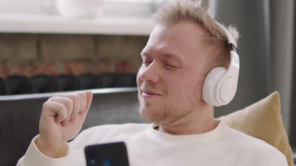 Cheerful Young Man in Headphones Enjoying Music