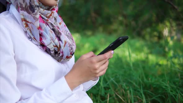 Muslim Girl with Cell in the Park