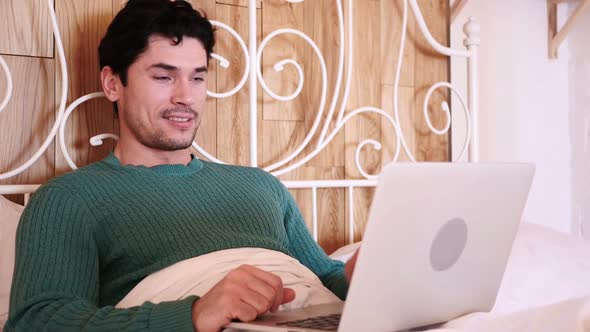 Online Video Chat on Laptop By Man Lying in Bed at Night