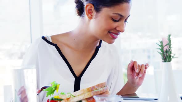 Woman eating lunch and using tablet computer