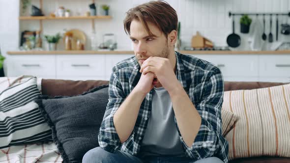 Sad Depressed Stressed Caucasian Man Sitting in the Living Room on the Couch Looking Ahead of