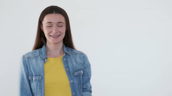 Young Smiling Woman with Braces on Teeth in Yellow and Blue Clothes on White Background Space for