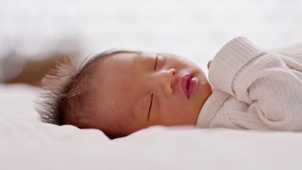 Close up happy newborn baby lying sleeps on a white blanket comfortable