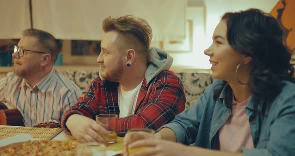 Young People Chatting at the Table Drinking Juice and Eating Pizza