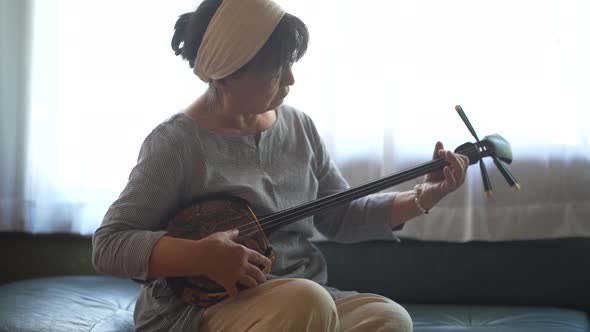 A woman practicing playing the sanshin