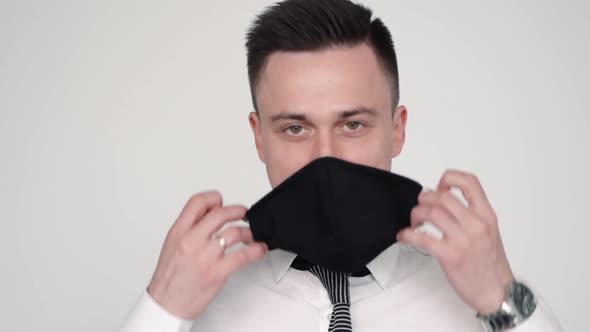 Front View of Young American Man Is Taking Off His Face Mask While Standing in Room.