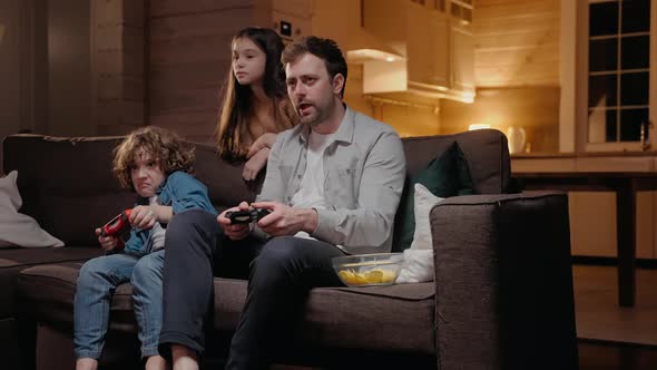 Father Playing with His Son in Game Console Laughing and Fighting on the Couch