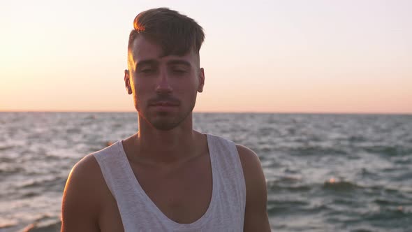 Portrait of Young Man on Concrete Pier with Rough Ocean Background Slow Motion