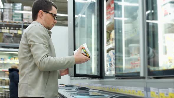 a Man Takes Out a Jar of Yogurt From the Refrigerator He Looks at the Label