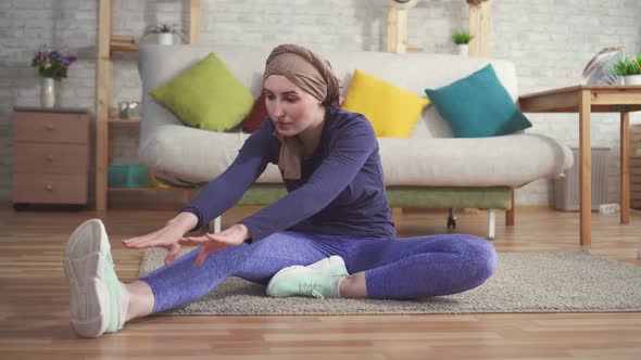 Young Woman Cancer Patient After Chemotherapy in a Scarf on the Head Does Stretching Before Training