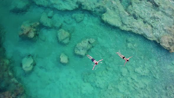 Aerial View of Couple Swim in Transparent Turquoise Sea Water Camera Rises Up