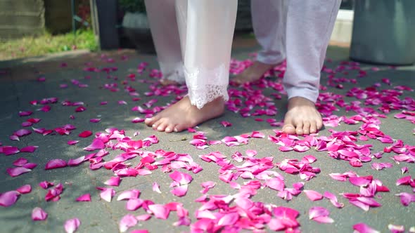 Legs of a man and a woman in white clothes on a background of rose petals	