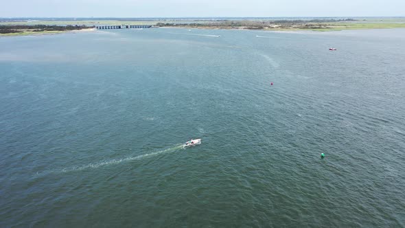 An aerial drone view over Jones Inlet on a sunny day. The camera truck right following a small boat