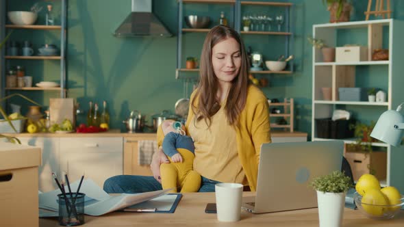 Happy Mother With the Child on the Hands Working Remotely From Home