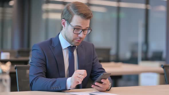 Businessman Celebrating Success on Smartphone