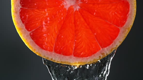 Super Slow Motion Macro Shot of Flowing Water From Grapefruit Slice on Black Background at 1000Fps