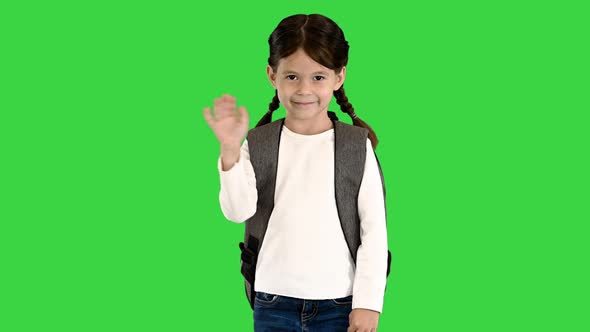 Cute Little Schoolgirl with Backpack Waving To the Camera on a Green Screen Chroma Key