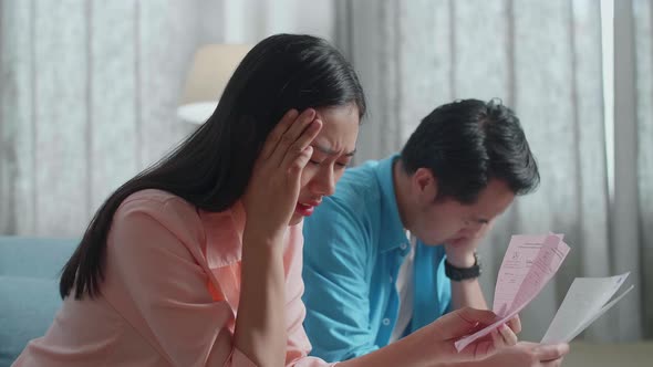 Close Up Of Asian Couple Looking At The Bill And Having Headache Due To Financial Problem