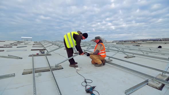 Workers building metal basis under blue cloudy sky