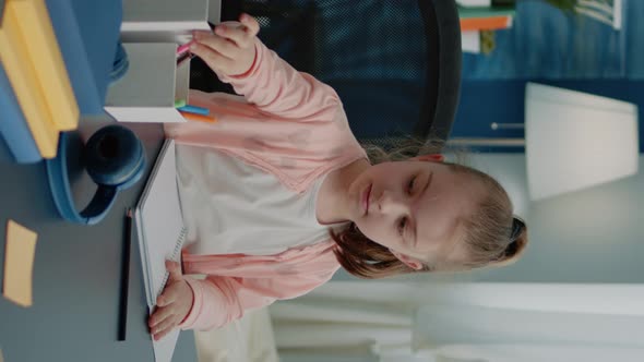 Vertical Video Schoolgirl Using Colorful Pencils to Draw on Notebook at Desk