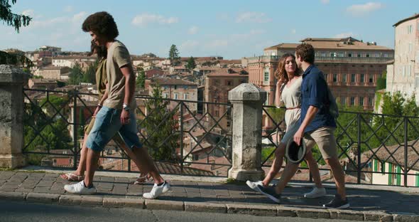 Four Happy Tourist People Walking Amazed Through Street Visiting Perugia Medieval city.Side Follow