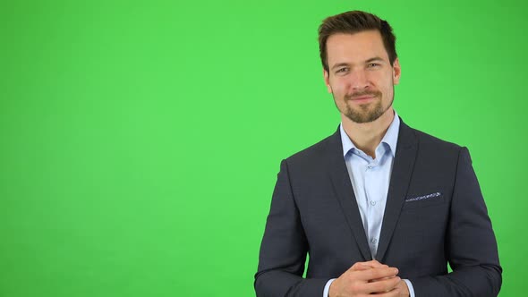 A Young Handsome Businessman Presents Something To the Camera with a Smile - Green Screen Studio