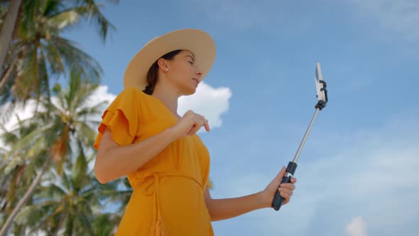 Lovely Girl in the Straw Hat Doing Online Report on the Ocean Beach Holding a Phone on Selfie Stick