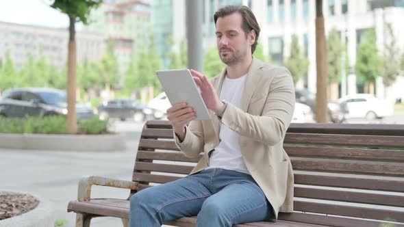 Young Man Using Tablet While Sitting on Bench