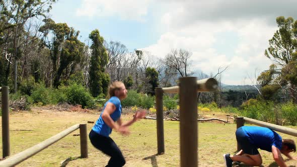 Fit man and woman climb a hurdles during obstacle course