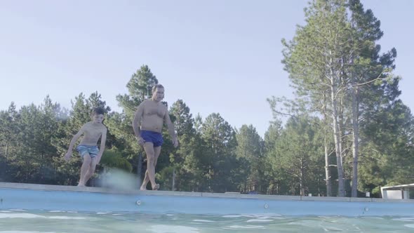 Man and boy diving into swimming pool together