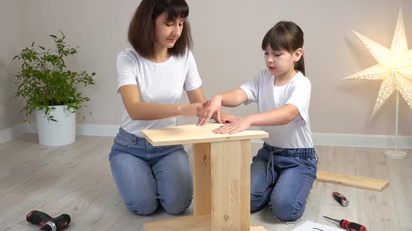 Happy Family Mother and Daughter Assembling Wooden Furniture Together