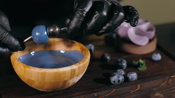 Pastry Chef is Making Artificial Berry for Topping a Blueberry Cake Closeup