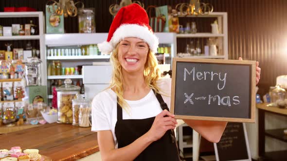 Portrait of waitress showing chalkboard with merry x-mas sign