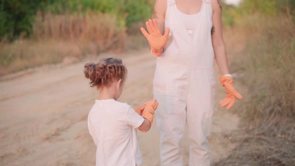 Little Girl Put on Gloves Give Five to Helps Mother Collects Plastic Garbage on Nature to Save