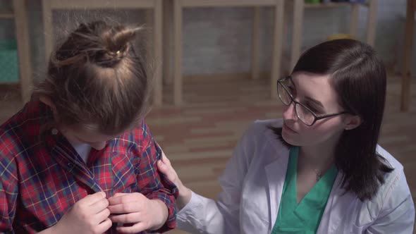 Dramatic Shot of a Sick Child and a Doctor in a White Coat Talking To a Patient of the Clinic