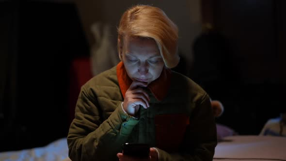 Devastated Woman Scrolling Smartphone Touchscreen Sitting in Bomb Shelter During Russian Bombardment