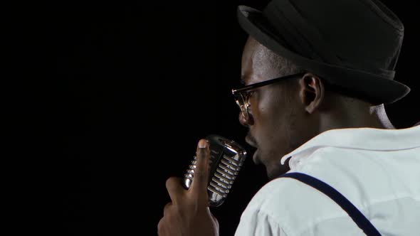 Singer the View From the Back Holding His Microphone and Gesticulating Hands Sings. Black Background