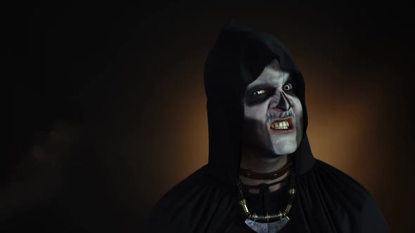 Creepy Man with Skeleton Makeup in Hood Making Angry Faces, Looking at Camera, Trying To Scare
